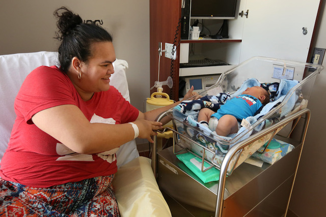 Gina Hilton reaches over to pick up her son Moses William Hilton, who fills his baby crib, at Hutchinson Regional Medical Center, in Hutchinson, Kan. Moses weighed over 14 pounds when he was born  ...
