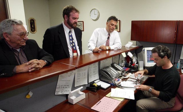 Chuck Patti, left, and Christopher Hansen, center, look on as political activist Tony Dane files paperwork with administrative assistant Jeff Fuell, right, Aug. 26, 2003. Dane and others are attem ...
