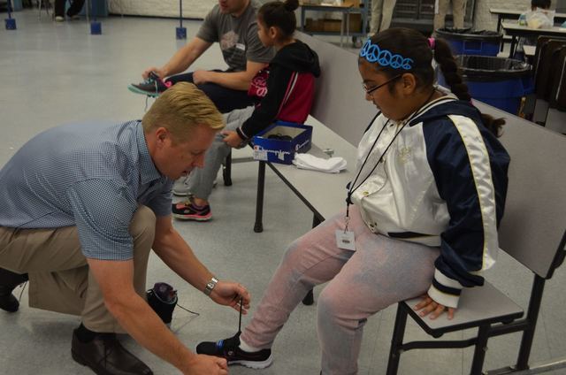 Las Vegas Southwest Rotary Club President Mitchell Horst helps fit a Ferron Elementary School student with new shoes during a Happy Feet distribution event May 17, 2016. Ginger Meurer/Special to View