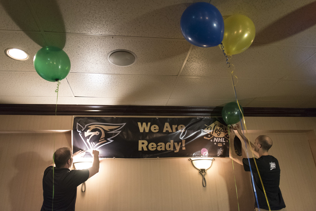 Eric Biro, left, and Ken Boehlke hang a hockey banner at O'Aces Bar & Grill following a conference in which the NHL's Board of Governors approved an expansion franchise in Las Vegas Wednesday, ...