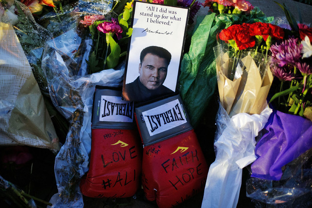 Boxing gloves and a message sit among flowers at a makeshift memorial to Muhammad Ali at the Muhammad Ali Center, Saturday, June 4, 2016, in Louisville, Ky. Muhammad Ali died Friday at age 74. (Da ...