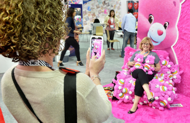 Holly Riehl, senior vice president at Rubik's Brand, left, takes a picture of Laura Pecci, senior vice president at Winning Moves Games, at the Care Bears booth during the Licensing Expo at the Ma ...