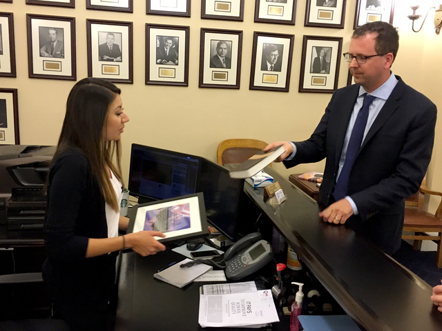 Alexei Laushkin, vice president of the Evangelical Environmental Network, presents a petition in support of rooftop solar to Jaqueline Pierrott, administrative assistant to Gov. Brian Sandoval, at ...