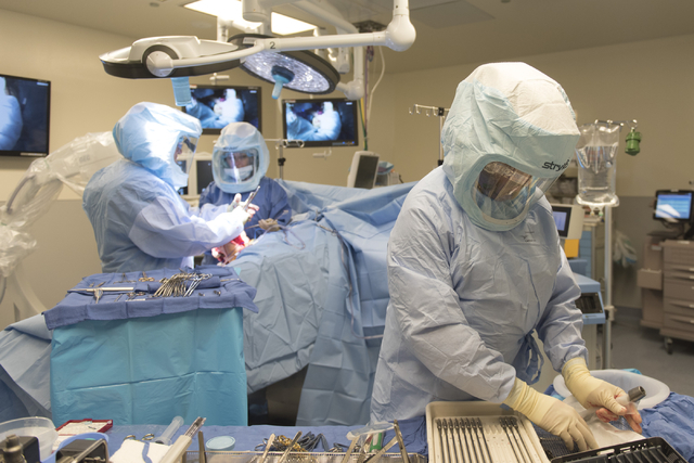 Jay French, certified scrub technician, right, Dr. Ronald Hillock, left, and Deanna Rechtzigel, advanced practice registered nurse, perform osseointegration surgery at Centennial Hills Hospital in ...