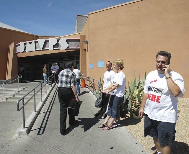 Political activist Tony Dane, right, talks on his cell phone while working with volunteers outside a DMV in Las Vegas, Sept. 8, 2003, where they are attempting to collect signatures for a recall e ...