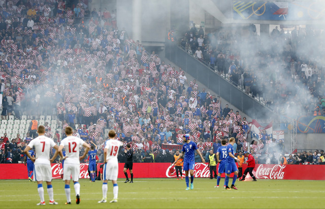 Players stand on the pitch after flares were thrown onto the pitch during the Euro 2016 Group D soccer match between the Czech Republic and Croatia at the Geoffroy Guichard stadium in Saint-Etienn ...