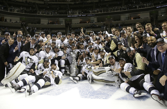 Pittsburgh Penguins players and coaches pose for photos with the Stanley Cup after Game 6 of the NHL hockey Stanley Cup Finals against the San Jose Sharks in San Jose, Calif., Sunday, June 12, 201 ...