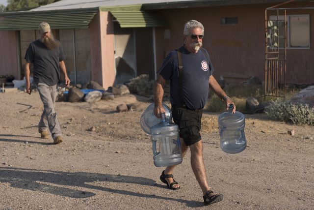 Larry Levy, fire chief with Southern Inyo Fire Protection District, right, and Jim Furlough, make their weekly potable water delivery rounds to residents in Tecopa, Calif. Tuesday, June 21, 2016.  ...