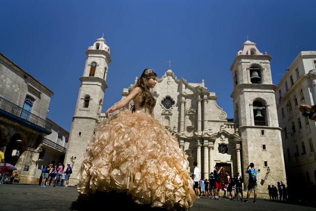 A "quinceanera" poses in front of the cathedral as tourists line up to enter the building, in Havana, March 14, 2016. Scheduled commercial airline service to Havana from 10 American cities won ten ...