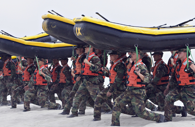 Navy SEAL trainees carry inflatable boats at the Naval Amphibious Base Coronado in Coronado, Calif., May 14, 2009. (Denis Poroy/AP)