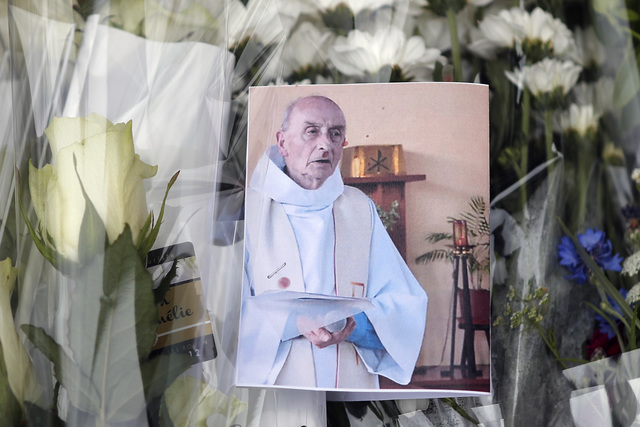 A picture of the late Rev. Jacques Hamel is placed on flowers at the makeshift memorial in front of the city hall close to the church where a hostage taking left the priest dead this week in Saint ...