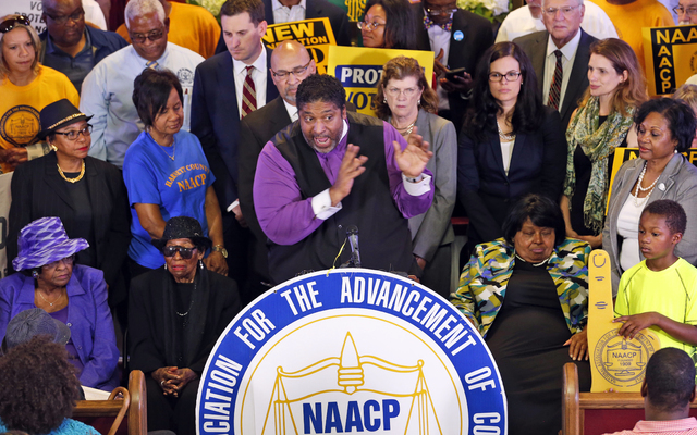File-This June 21, 2016, file photo shows North Carolina NAACP president, Rev. William Barber, center at podium gesturing during a news conference in Richmond, Va. (AP Photo/Steve Helber, File)