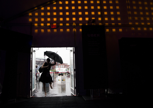 Covention attendees rush to get out of the rain at the Uber tent during the final day of the Democratic National Convention at the Wells Fargo Center on Thursday, July 28, 2016, in Philadelphia. B ...