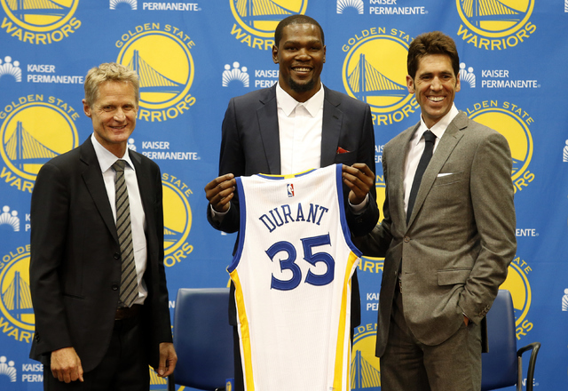 Golden State Warriors' newest player Kevin Durant, center, joins head coach Steve Kerr, left and general manager Bob Myers during a news conference at the NBA basketball team's practice facility,  ...