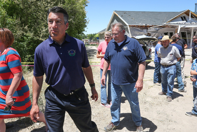 Nevada Governor Brian Sandoval, left, leaves a briefing at the site of the Wednesday night bombing on Friday, July 15, 2016, at the attacked house in Panaca, Nev. The bombing killed one person. Br ...