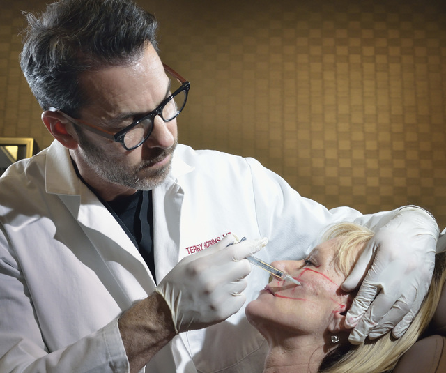 Dr. Terry Higgins injects a patient with a compound used to fill hollows in the face and make cheekbones look fuller at Anson and Higgins Plastic Surgery Associates in this file photo. (Bill Hughe ...