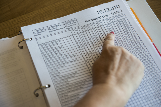 Julie Davies shows permit policies while speaking to a reporter during an interview regarding the city's licensing and zoning regulations on short-term residential rentals from a Starbucks on Nort ...