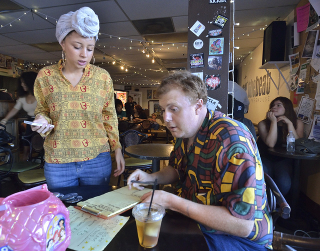 Organizer Andy Hall, right, helps Lo Campbell sign in during a poetry slam sponsored by the Battle Born slam poetry team at The Beat Coffeehouse and Records at 520 Fremont St. in Las Vegas on Frid ...