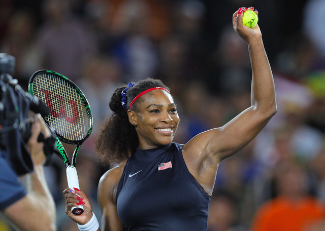 Serena Williams of the United States prepares to shoot an autographed ball into the tribune after defeating France's Alize Cornet in the women's tennis competition at the 2016 Summer Olympics in R ...