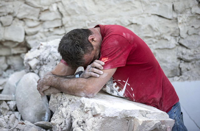 A man leans on rubble following an earthquake in Amatrice Italy, Wednesday, Aug. 24, 2016.  A strong earthquake in central Italy reduced three towns to rubble as people slept early Wednesday. (Mas ...