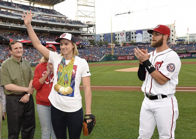 Olympic gold medal swimmer Katie Ledecky acknowledges the crowd while standing next to Washington Nationals' Bryce Harper, right, before a baseball game between the Baltimore Orioles and the Natio ...