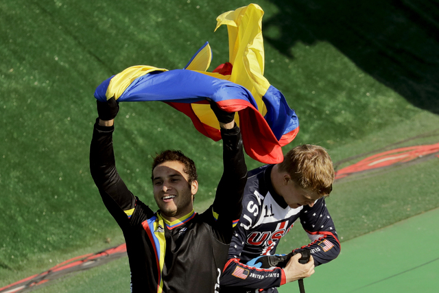 Third placed Carlos Ramirez Yepes of Colombia, left, waves a Colombian flag next to first placed Connor Fields of the United States after the men's BMX cycling final during the 2016 Summer Olympic ...