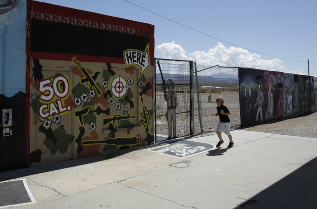 A young person runs by the Last Stop outdoor shooting range Wednesday, Aug. 27, 2014, in White Hills, Ariz. Gun range instructor Charles Vacca was accidentally killed Monday, Aug. 25, 2014, at the ...