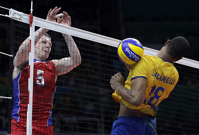 Russia's Sergey Grankin, left, scores past Brazil's Ricardo Lucarelli during a men's semifinal volleyball match at the 2016 Summer Olympics in Rio de Janeiro, Brazil, Friday, Aug. 19, 2016. (AP Ph ...