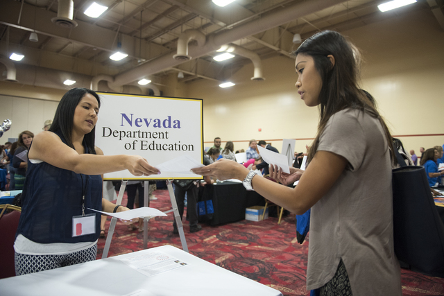Nevada Department of Education employee Cynthia Santos, left, hands out pamphlets to Christine Tran, an incoming teacher, during a Clark County School District event to launch the 2016-17 academic ...