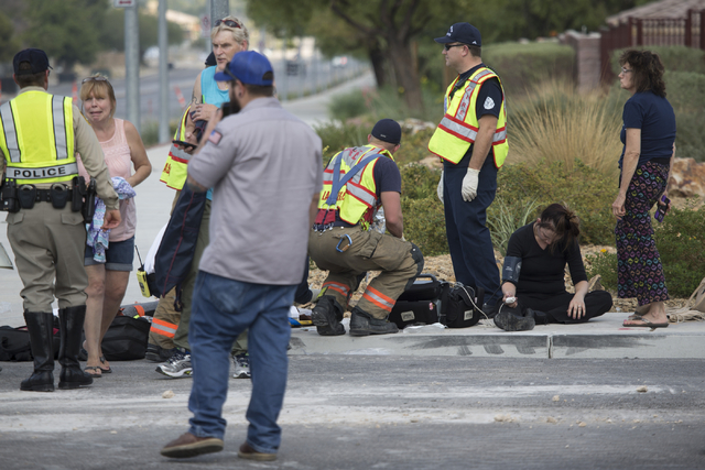 A woman is assisted by paramedics at the scene of a two car crash at the intersection of North Fort Apache Road and West Lone Mountain Road is seen on Wednesday, Aug. 24, 2016, in Las Vegas. Erik  ...