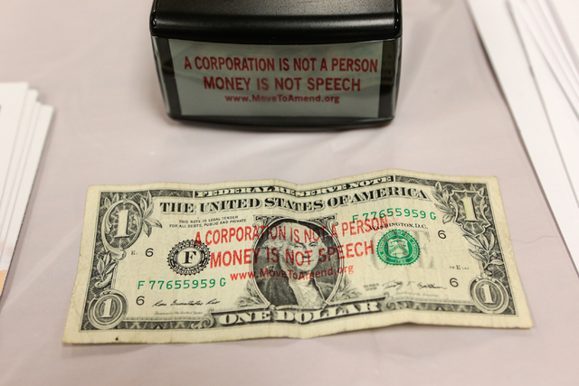 A stamped dollar bill and a stamper are shown at the Move to Amend information table during the "Our Revolution" kickoff party at the Veterans of Foreign Wars Center, 4337 N Las ...