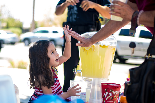 Theresa Ann Babcock, 3, gets a high-five at her lemonade stand outside of Henderson City Hall July 19. Elizabeth Brumley/View