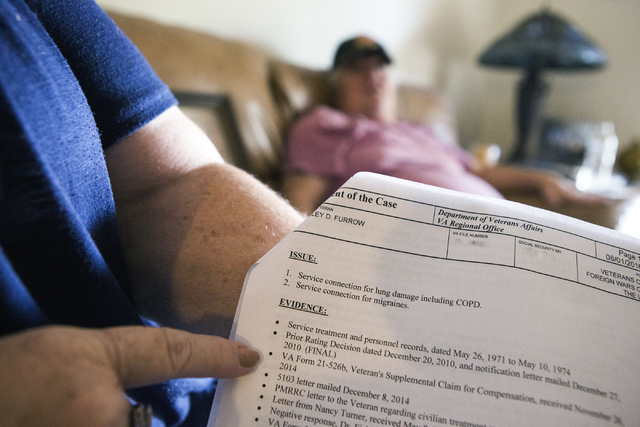Linda Furrow, points to evidence on a Veterans Affairs form showing the family health issues while her husband, Marine veteran Stanley Furrow, sits in the family's home in Las Vegas on Thursday, A ...