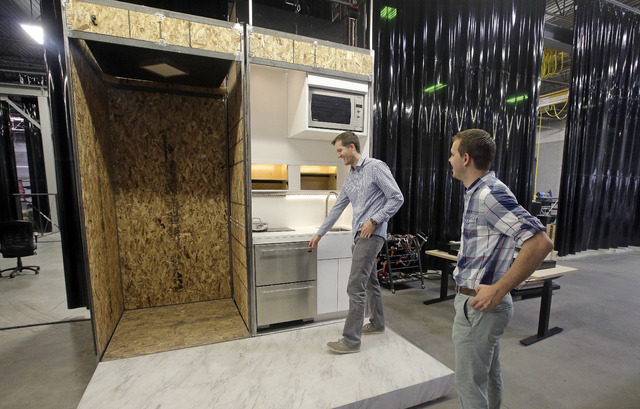 Andrew Priddis, left, stands in front of kitchen for a new type of modular residential structure Friday, Aug. 19,2016, in Provo, Utah. (Rick Bowmer/The Associated Press)