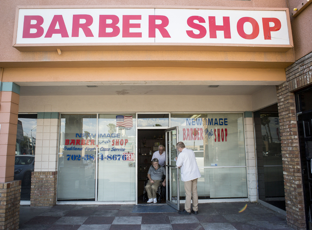 Barbers Jon Holten, left, and Randy Benefiel, right, help their client, who has been their client for 20 years, to leave after cutting hair at New Image Barber & Styling, Wednesday, Aug. 17, 2 ...