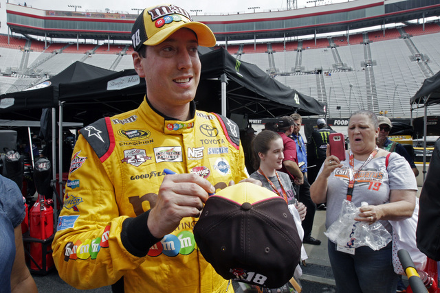 Kyle Busch signs an autograph as he walks through the pit area after practice for a NASCAR Sprint Series auto race on Friday, Aug. 19, 2016, in Bristol, Tenn. (AP Photo/Wade Payne)