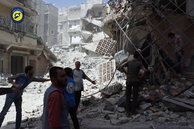 In this photo provided by the Syrian Civil Defense White Helmets, men stand amid rubble after airstrikes in al-Mashhad neighborhood in the rebel-held part of eastern Aleppo, Syria, Wednesday Sept. ...