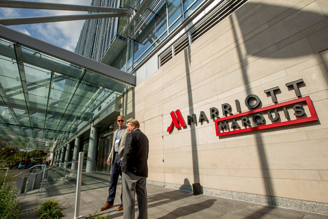 FILE - In this Wednesday, Oct. 14, 2015, file photo, two men stand outside the newly-built Marriott Marquis hotel in Washington. Marriott International closed early Friday, Sept. 23, 2016, on its ...