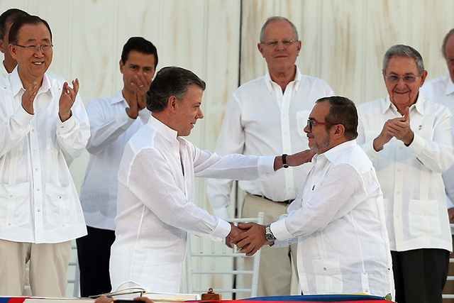 Colombia’s President Juan Manuel Santos, front left, and the top commander of the Revolutionary Armed Forces of Colombia (FARC) Rodrigo Londono, known by the alias Timochenko, shake hands after ...