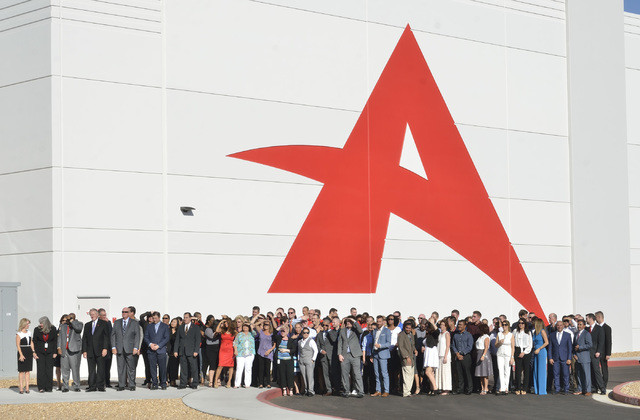 A group of people waits to have a photo taken during grand opening ceremonies for the new North American headquarters of Ainsworth Game Technology at 5800 Rafael Rivera Way in Las Vegas on Friday, ...