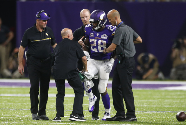 Minnesota Vikings running back Adrian Peterson (28) is helped off the field after getting injured during the second half of an NFL football game against the Green Bay Packers Sunday, Sept. 18, 201 ...