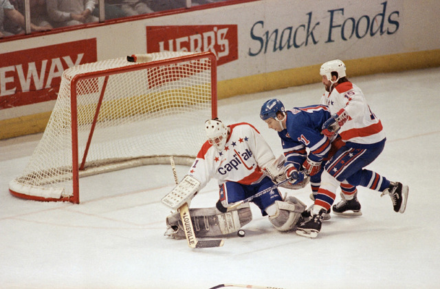 Washington Capitals goalie Mike Liut, left, makes the stop on New York Rangers center Kelly Kisio's shot on goal between the defence of capitals defenseman Neil Sheehy during the second period of  ...