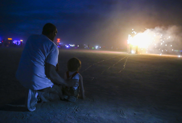 Pyrotechnician Eric Rebollo, or Big E, his playa name, helps Sagan Bocskor, 5, set his art piece "Jedi Dog Temple" to burn during Burning Man at the Black Rock Desert north of Reno on Thursday, Se ...