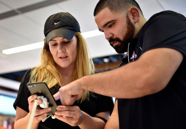 Kim Katunis, left, with the assistance of salesperson Mando Meza looks over a iPhone 7 Plus at an AT&T store Friday, Sept. 16, 2016, in Las Vegas.  Apple's newest iPhone went on sale on Friday ...