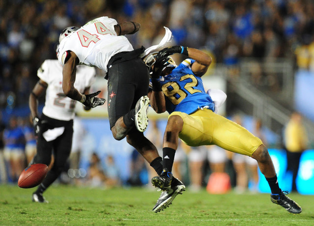 UNLV Rebels defensive back Kenny Keys (44) hits UCLA Bruins wide receiver Eldridge Massington (82) in the second half of their NCAA college football game at the Rose Bowl in Pasadena, Calif. Satur ...