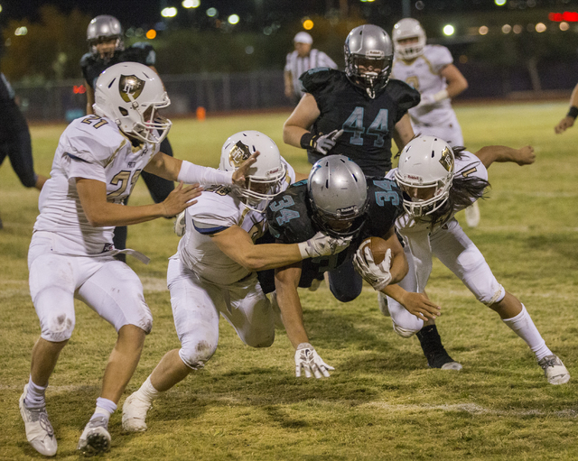 Silverado running back Keikiokalani Misipeka (34) is tackled by a group of Faith Lutheran defenders during the Skyhawks home matchup with the Faith Lutheran Crusaders on Friday, Sept. 16, 2016, at ...