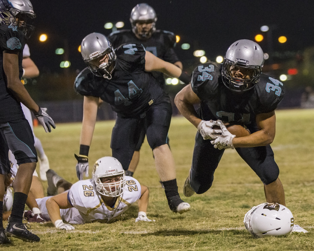 Silverado running back Keikiokalani Misipeka (34) avoids a loose helmet as he runs down the sideline during the Skyhawks home matchup with the Faith Lutheran Crusaders on Friday, Sept. 16, 2016, a ...