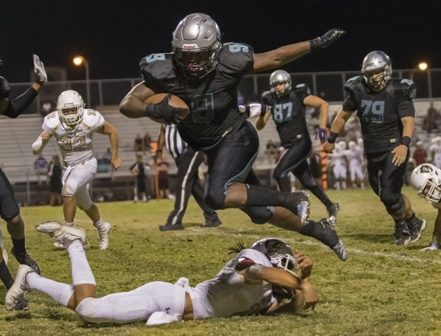 Silverado running back Nahzi Salih (9) leaps over a Faith Lutheran defender during the Skyhawks home matchup with the Crusaders on Friday, Sept. 16, 2016, at Silverado High School, in Las Vegas. B ...