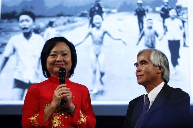 Photojournalist Nick Ut, right, and Kim Phuc attend a photography conference in 2012. Ut took the iconic 1972 Vietnam War photograph (seen in the background) of Phuc running down a road after bein ...