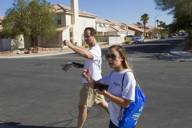 Tim Phillips, left, president of Americans for Prosperity and Field Director Erinn Mahathey walk door-to-door while canvassing a neighborhood for the organization in west Las Vegas on Monday, Aug. ...